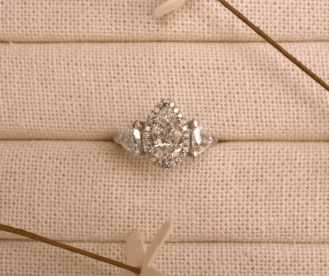 Close-up of a pear-shaped diamond halo engagement ring in a jewelry box.